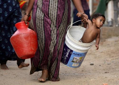 مادر هندی در کنار تانکر توزیع آب در شهر 